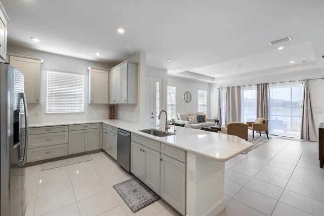 a large white kitchen with a sink large mirror and cabinets