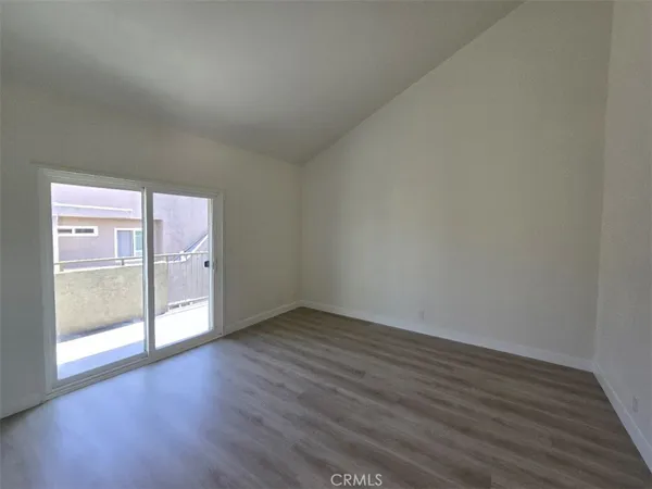 a view of an empty room with wooden floor and glass door