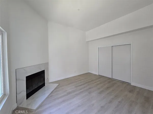 a view of empty room with wooden floor and fireplace