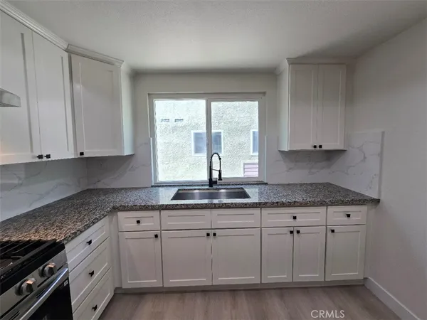 a kitchen with granite countertop white cabinets white appliances and sink