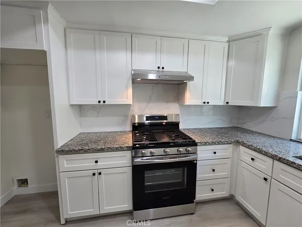 a kitchen with granite countertop white cabinets and stainless steel appliances