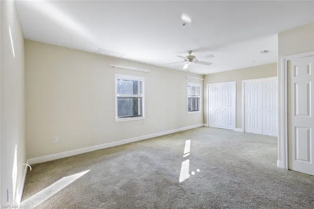 an empty room with windows and ceiling fan
