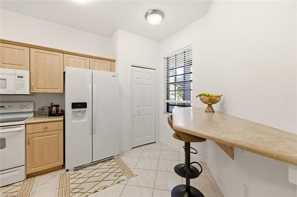 14978 Summit Pl Circle Naples, FL 34119 - Photo 11 of 35 Kitchen with light brown cabinets, white appliances, light tile patterned floors, and light countertops