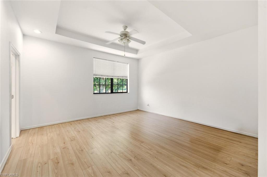 14978 Summit Pl Circle Naples, FL 34119 - Photo 15 of 35 Spare room with a raised ceiling, light wood-style flooring, and a ceiling fan