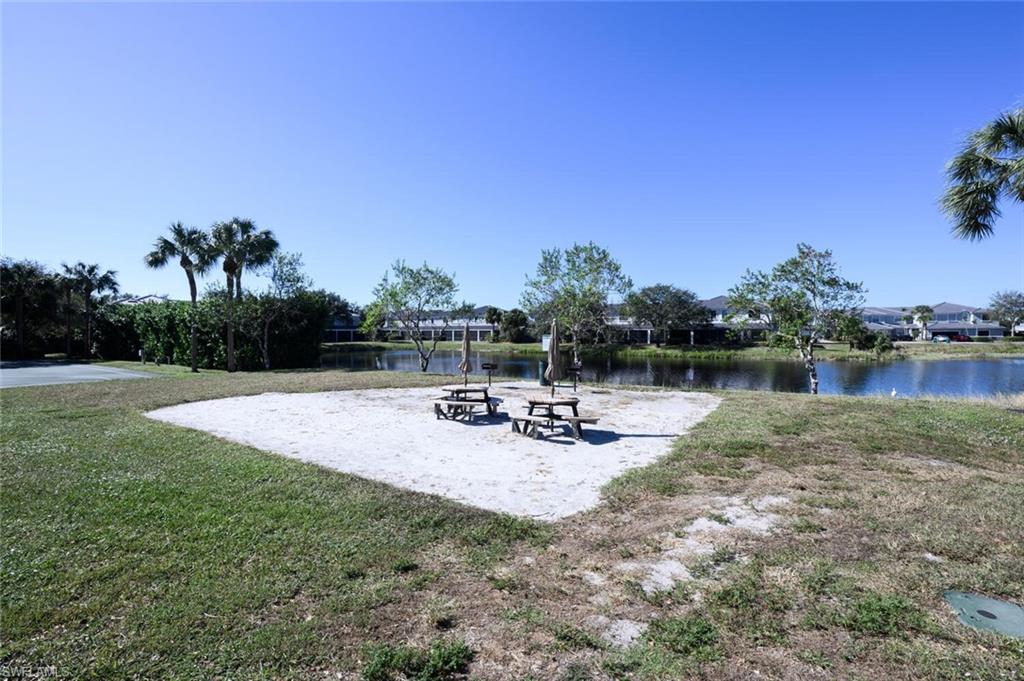14978 Summit Pl Circle Naples, FL 34119 - Photo 34 of 35 View of community featuring a patio, a lawn, and a water view