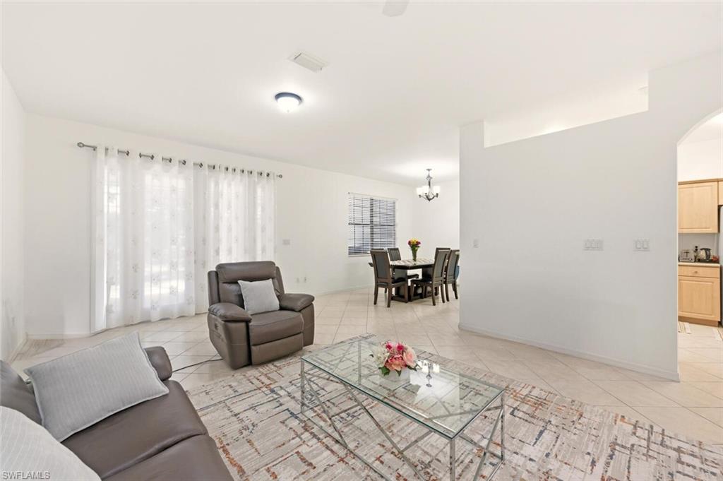 14978 Summit Pl Circle Naples, FL 34119 - Photo 6 of 35 Living room with light tile patterned floors, a chandelier, and arched walkways