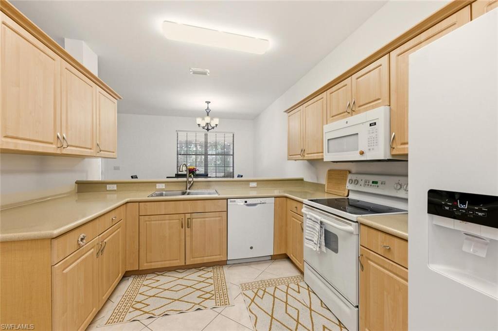 14978 Summit Pl Circle Naples, FL 34119 - Photo 10 of 35 Kitchen featuring white appliances, light brown cabinetry, and a chandelier