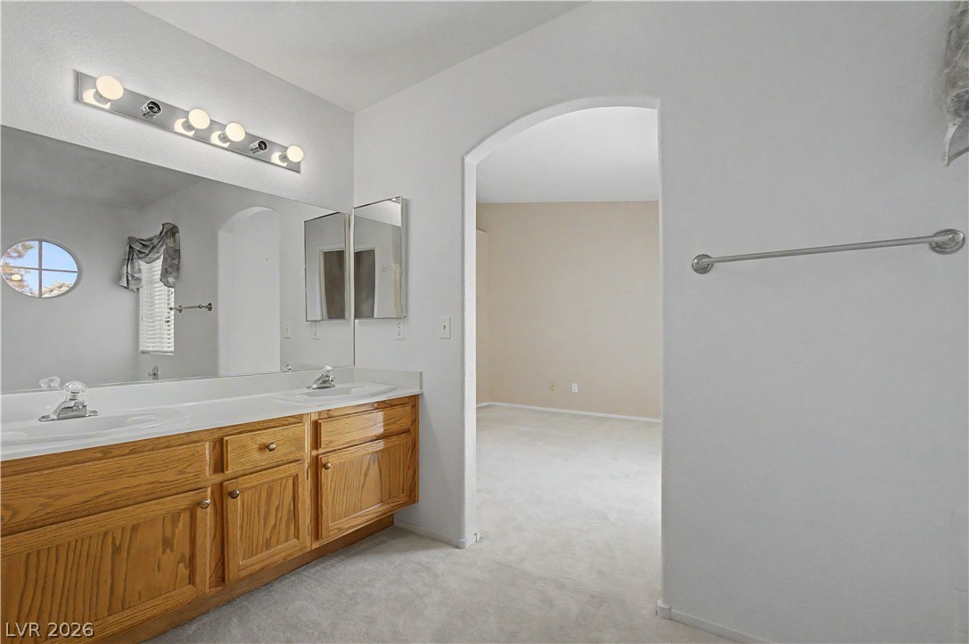 2243 Rugged Mesa Drive Laughlin, NV 89029 - Photo 19 of 32 A well-lit primary bathroom featuring a double vanity with ample counter space and an arched entryway to the primary bedroom.