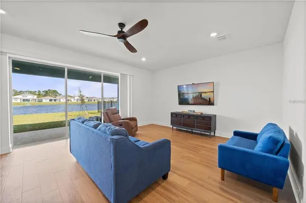 a living room with furniture ceiling fan and a floor to ceiling window