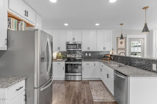 a kitchen with stainless steel appliances granite countertop a refrigerator a stove a sink a dining table and chairs with wooden floor