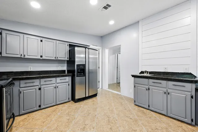 a kitchen with stainless steel appliances granite countertop a stove a sink and a refrigerator
