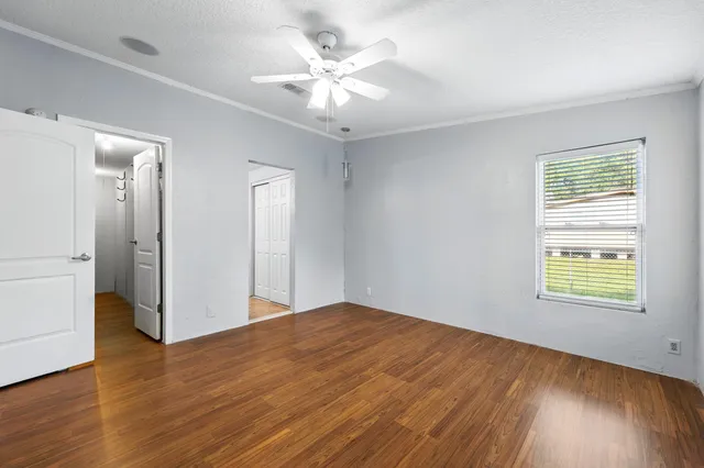 a view of an empty room with wooden floor and a window