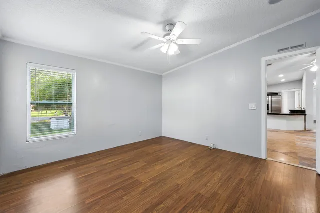 a view of an empty room with wooden floor and a window