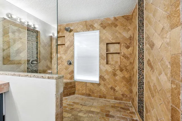 a bathroom with a granite countertop shower and a mirror