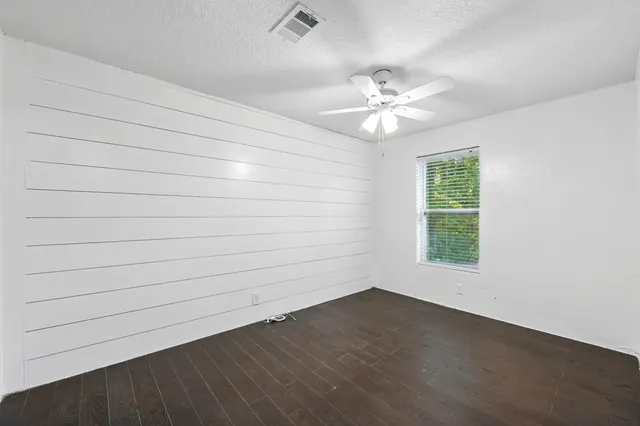 an empty room with a window and a ceiling fan
