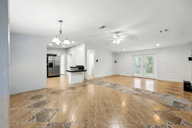 a view of an empty room and kitchen view with wooden floor