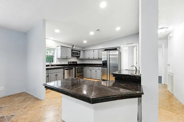 a kitchen with stainless steel appliances granite countertop a sink a stove and a refrigerator