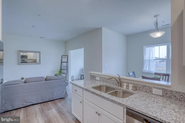 a kitchen with granite countertop a sink and a wooden floor