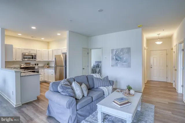 a living room with stainless steel appliances kitchen island granite countertop a refrigerator and a sink