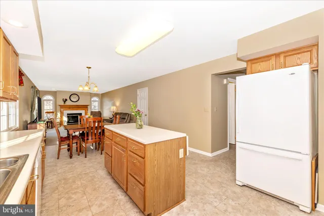 a large kitchen with a refrigerator a stove a sink dishwasher a dining table and chairs with wooden floor