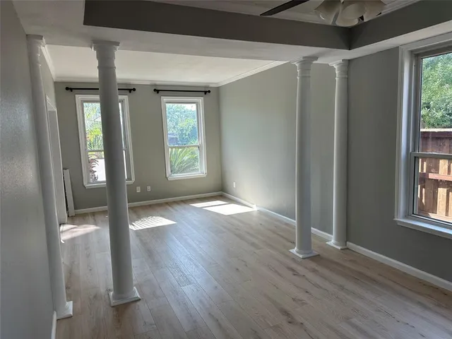 an empty room with wooden floor and windows