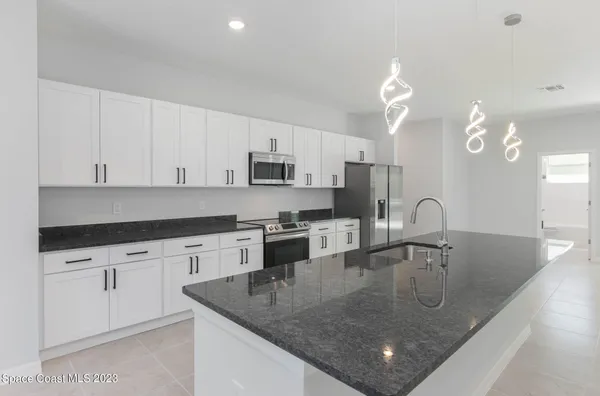 a kitchen with kitchen island granite countertop a sink a center island and cabinets