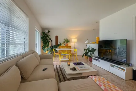 a living room with furniture a flat screen tv and a large window