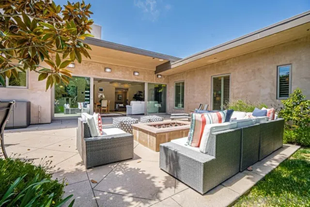 a view of a patio with couches table and chairs potted plants and large tree