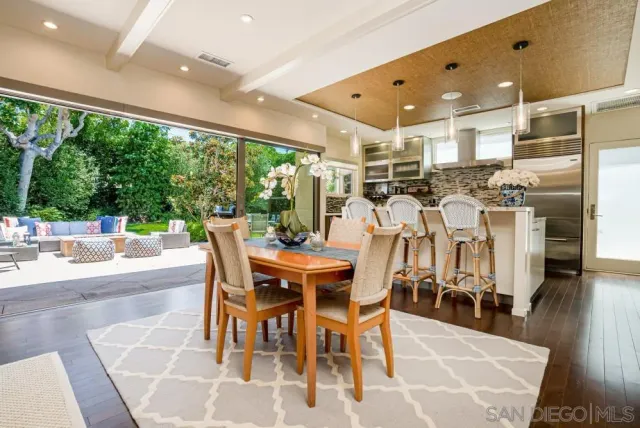 a dining hall with stainless steel appliances kitchen island granite countertop a table and chairs with the wooden floor