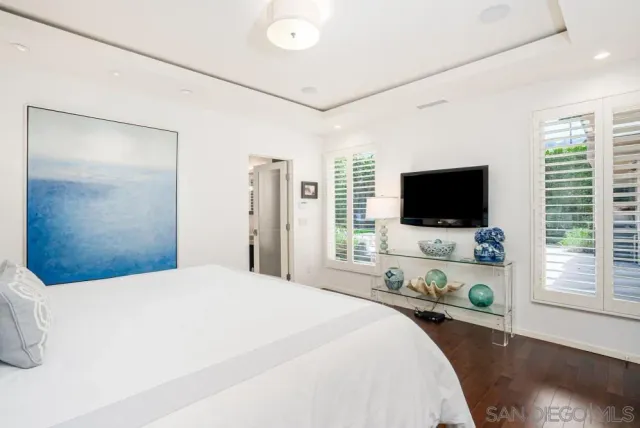 a bedroom with a bed and a flat tv screen on dresser