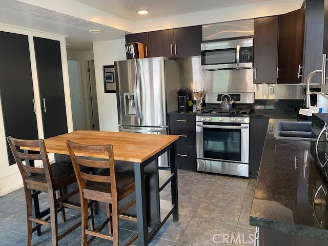 a kitchen with stainless steel appliances granite countertop a stove a refrigerator and a fireplace