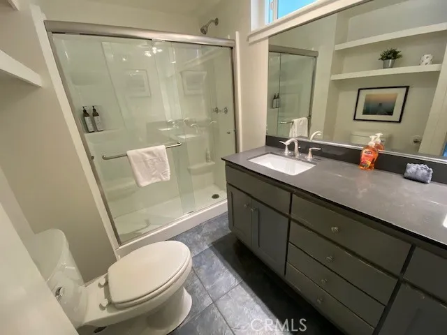 a bathroom with a granite countertop sink toilet a mirror and shower