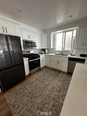 a kitchen with stainless steel appliances granite countertop a refrigerator sink stove microwave and cabinets