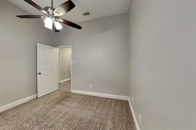 an empty room with a chandelier fan and a ceiling fan