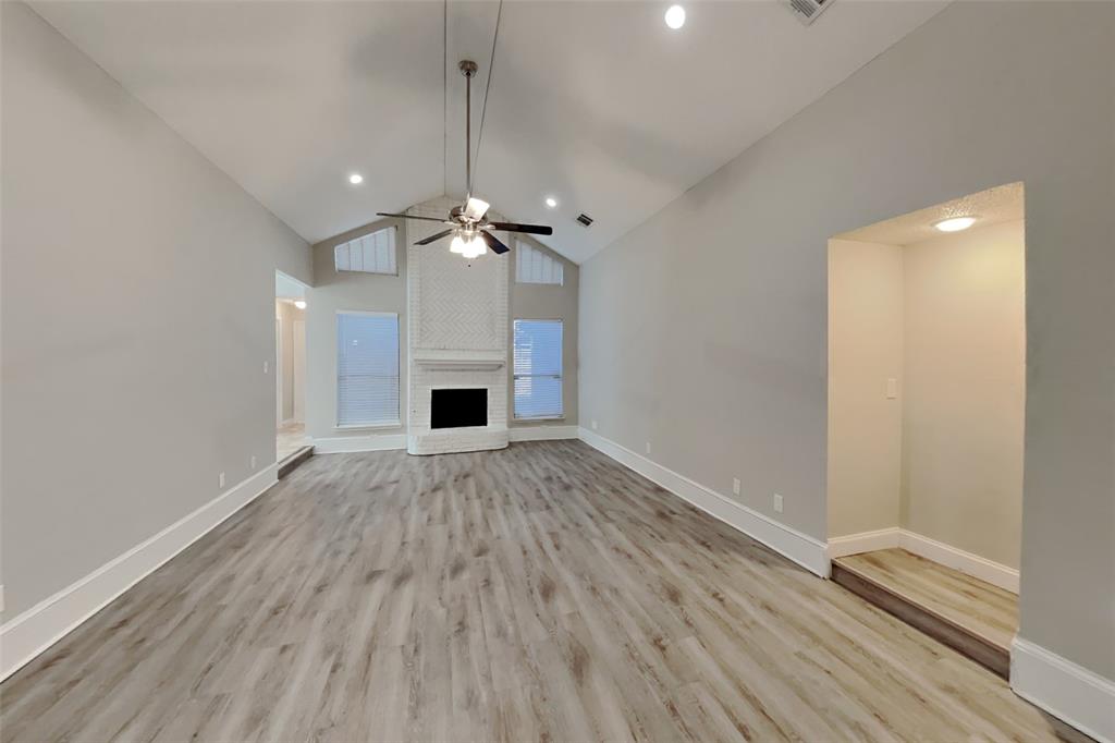 1009 Schrade Trail Mesquite, TX 75181 - Photo 2 of 19 Unfurnished living room featuring high vaulted ceiling, light wood-style floors, a fireplace, and a ceiling fan