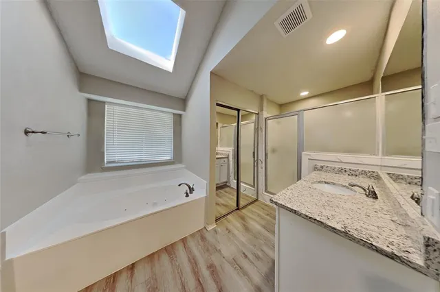 a bathroom with a granite countertop sink a mirror and a bathtub