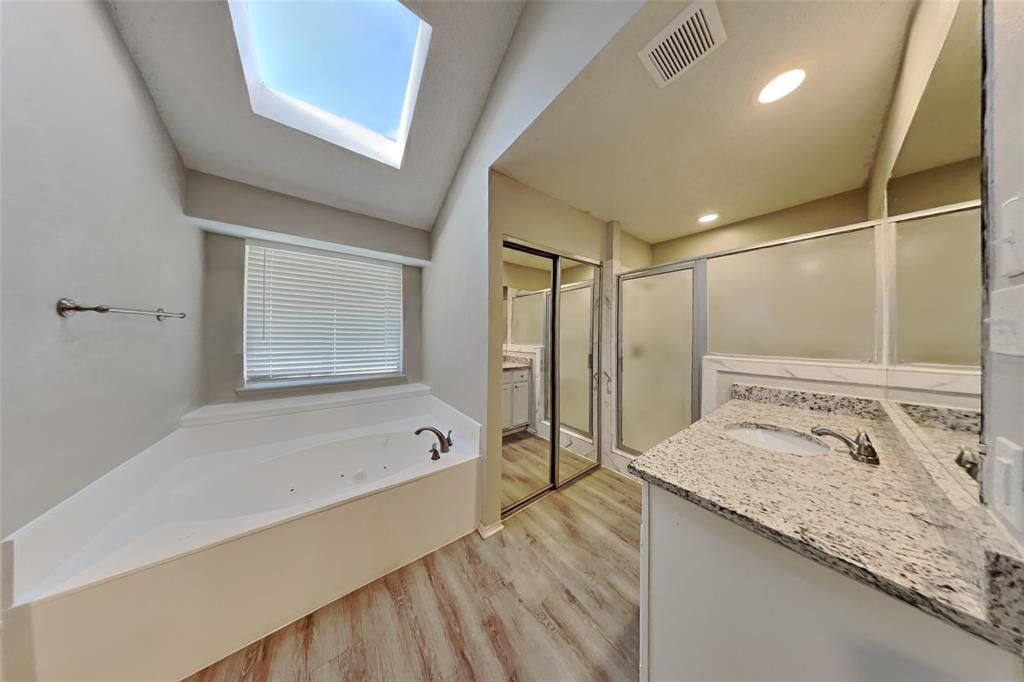1009 Schrade Trail Mesquite, TX 75181 - Photo 8 of 19 Full bathroom featuring vanity, a stall shower, a whirlpool tub, a skylight, and light wood-style floors