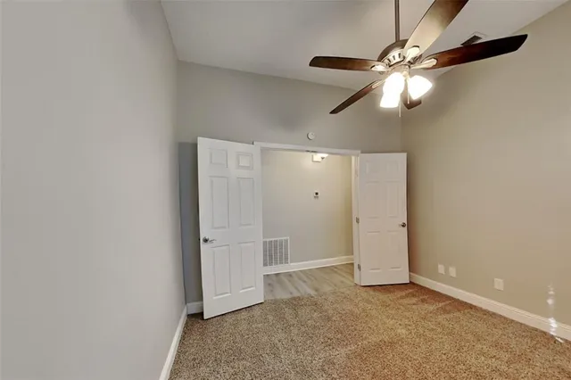 an empty room with closet and fan