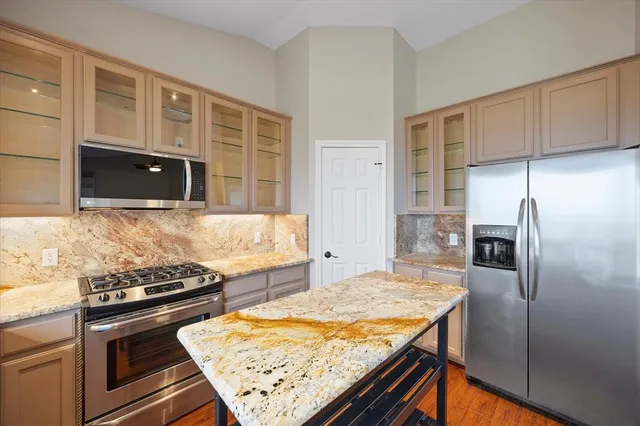 a kitchen with stainless steel appliances granite countertop a refrigerator and a stove top oven
