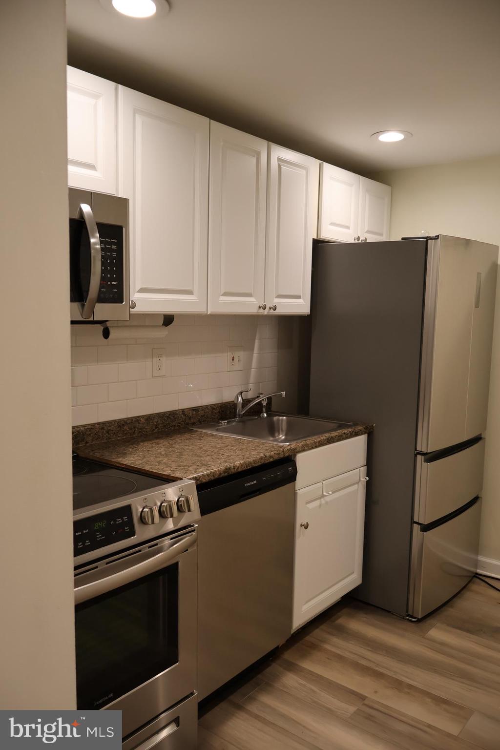 33 South 19th Street Philadelphia, PA 19103 - Photo 10 of 25 a kitchen with granite countertop a refrigerator stove and white cabinets