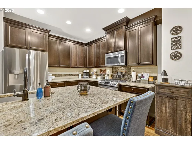 a kitchen with stainless steel appliances granite countertop a sink refrigerator and cabinets
