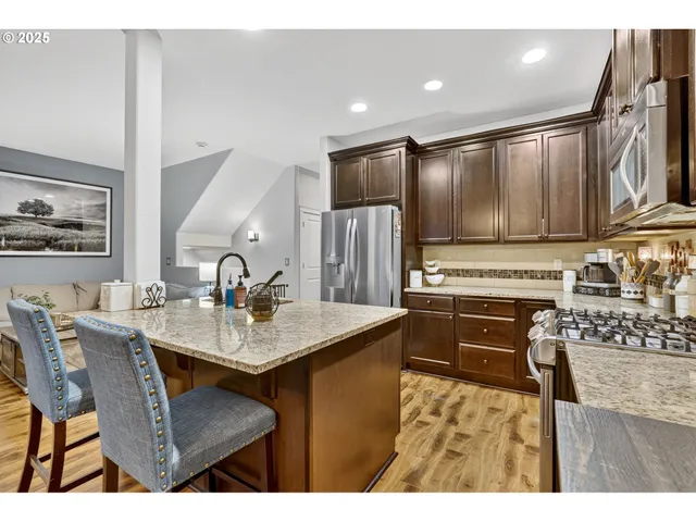 a kitchen with kitchen island granite countertop a sink stove and refrigerator