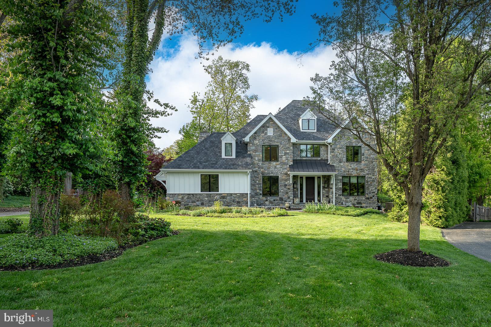 a front view of a house with a garden and trees