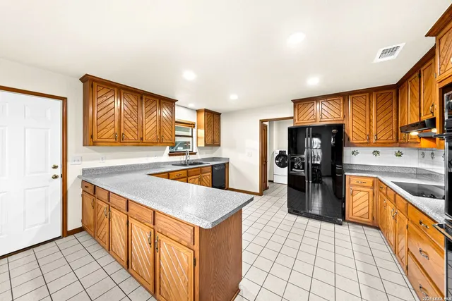 a large kitchen with stainless steel appliances granite countertop a large window a sink and cabinets