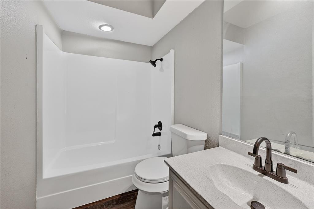 9809 Matchpoint Place Dallas, TX 75243 - Photo 15 of 21 Upstairs Bathroom featuring a white shower-tub combination with dark bronze fixtures, a white toilet, and a vanity with a white countertop and integrated sink