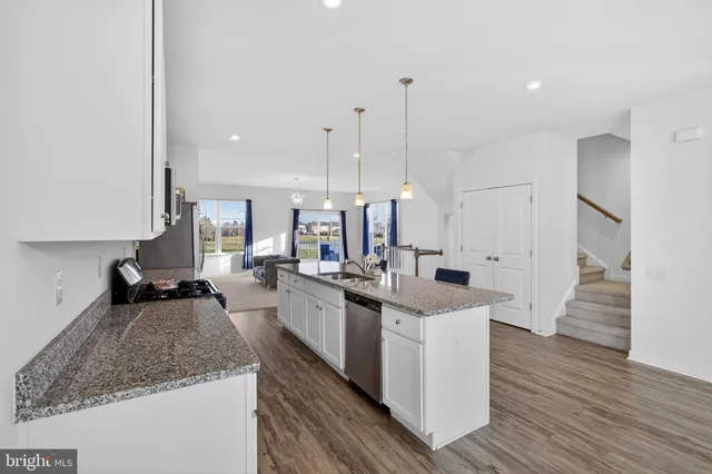 a kitchen with stainless steel appliances granite countertop a sink a stove and a wooden floors