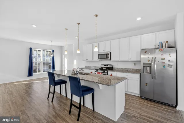 a kitchen with refrigerator and wooden floor