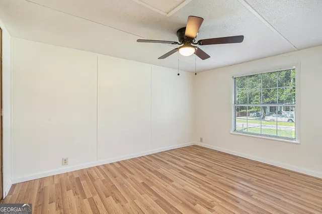 a view of an empty room with wooden floor and a window