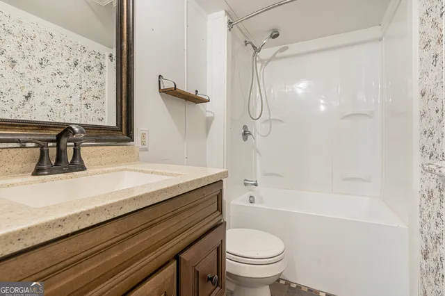 a bathroom with a granite countertop sink a toilet and shower