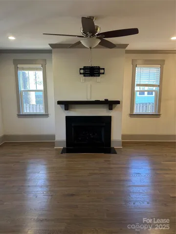 a view of an empty room with wooden floor and a fireplace